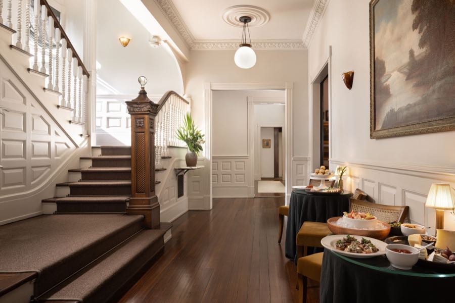 The entry hall dressed for evening canapés, with skirted tables and an oil painting above