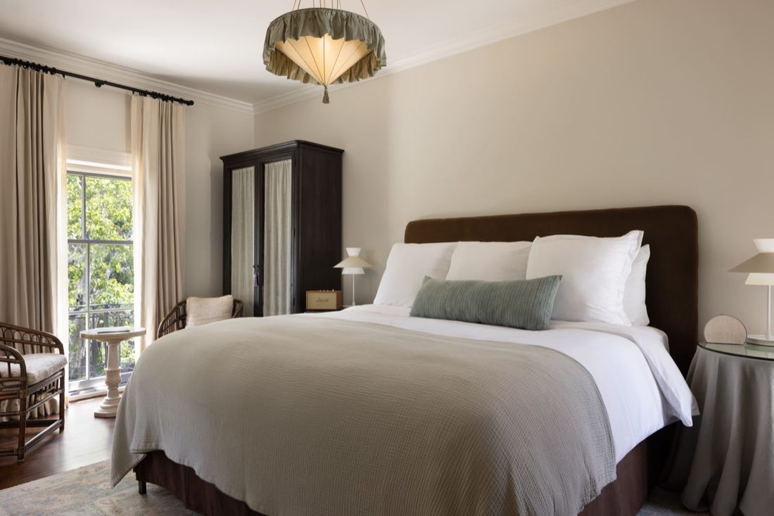 Room Twelve, a dark upholstered headboard under a fringed pendant, a tall armoire alongside.