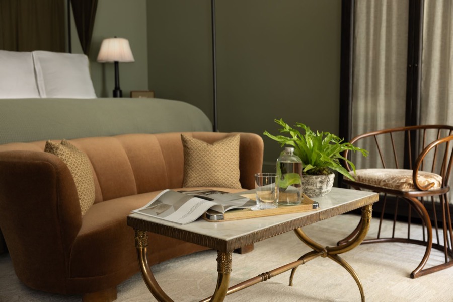 A brown mohair sofa and a brass-and-marble coffee table against olive walls