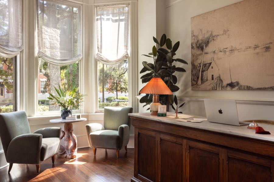 The front desk set in a bay window, with a coral pleated lamp