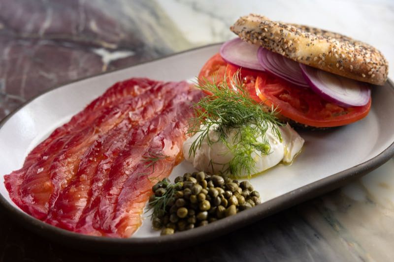 Bagel and lox: house-cured beet and horseradish salmon on an everything bagel with tomato, capers and dill