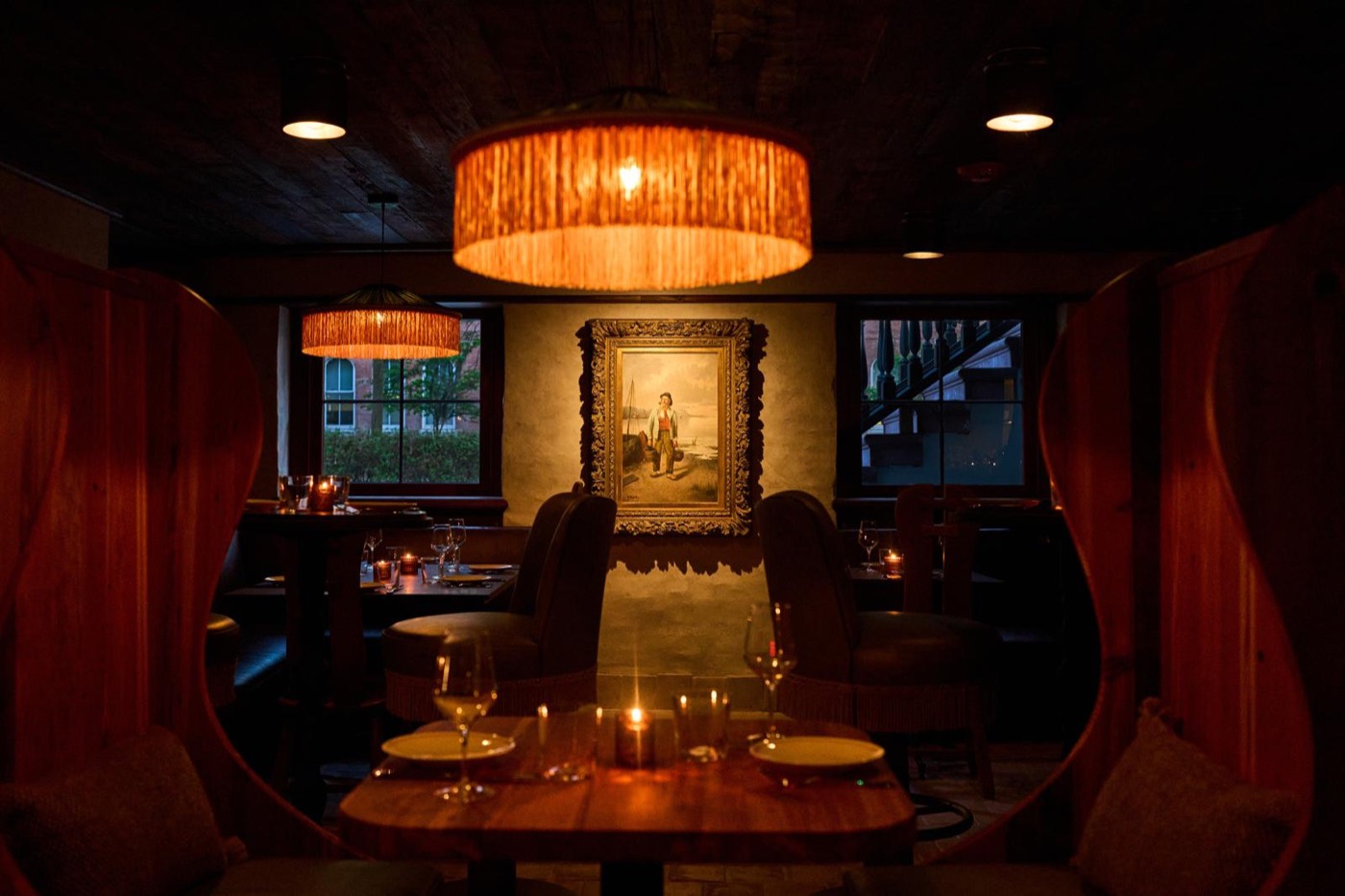 Lester's dining room at night: drum shades, oxblood banquettes and candlelit tables beneath a gilt-framed painting