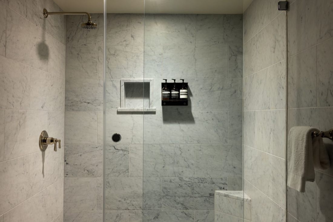 The shower in Room Three, Carrara marble with a rainhead, a niche and a bench.