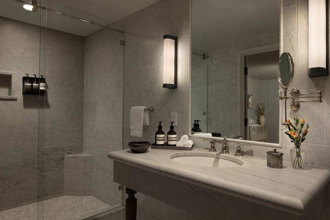 The bathroom in Room Three, grey marble and a wall-mounted vanity beside a walk-in shower.