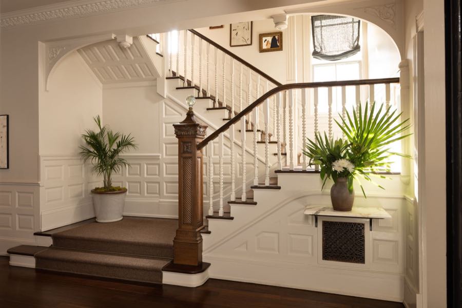 The entry hall staircase, white panelling and a carved newel post